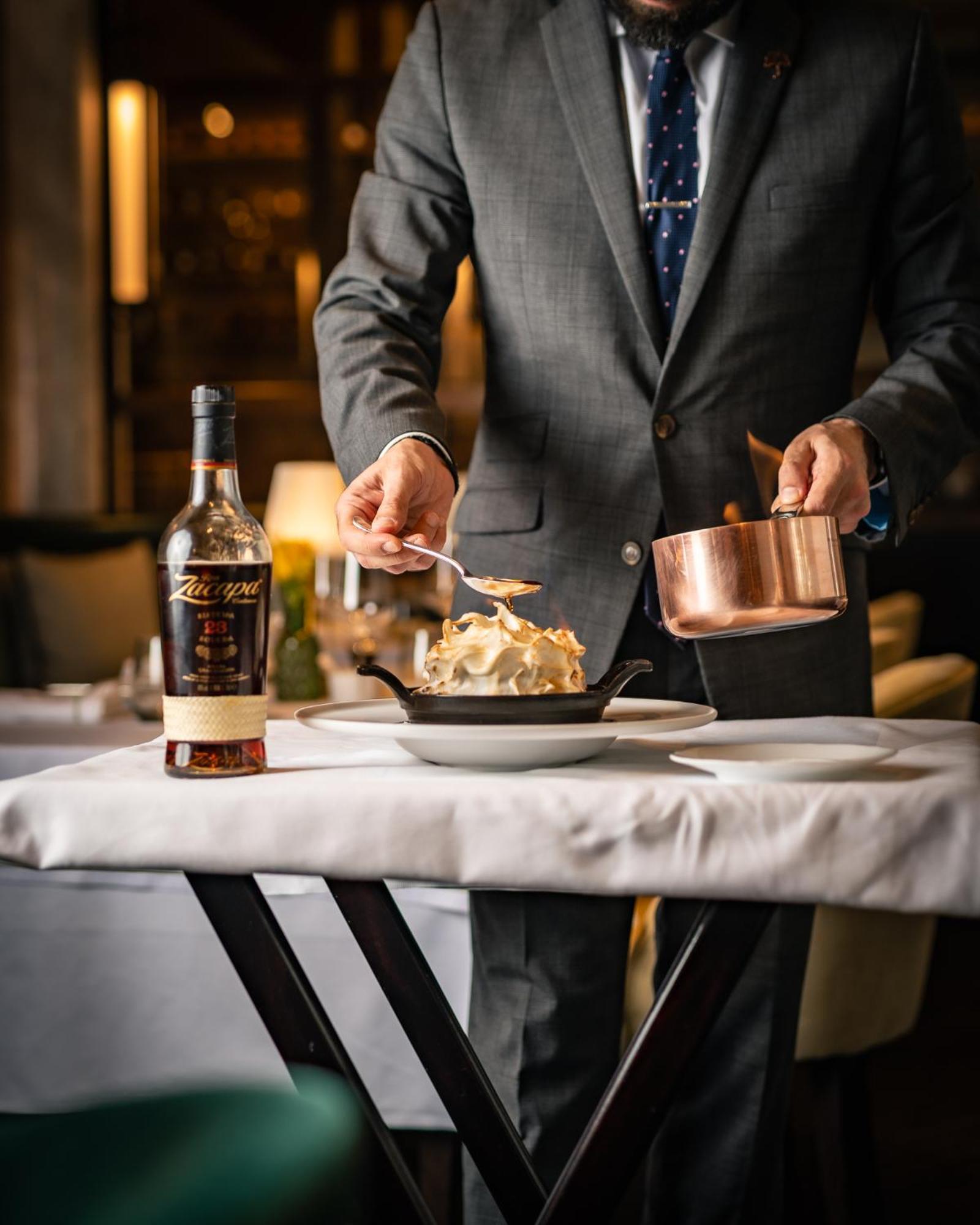 The Biltmore Mayfair Лондон Экстерьер фото A server prepares a dish at the restaurant.
